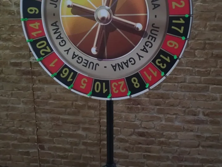 Small prize wheel on a tripod against a brick wall