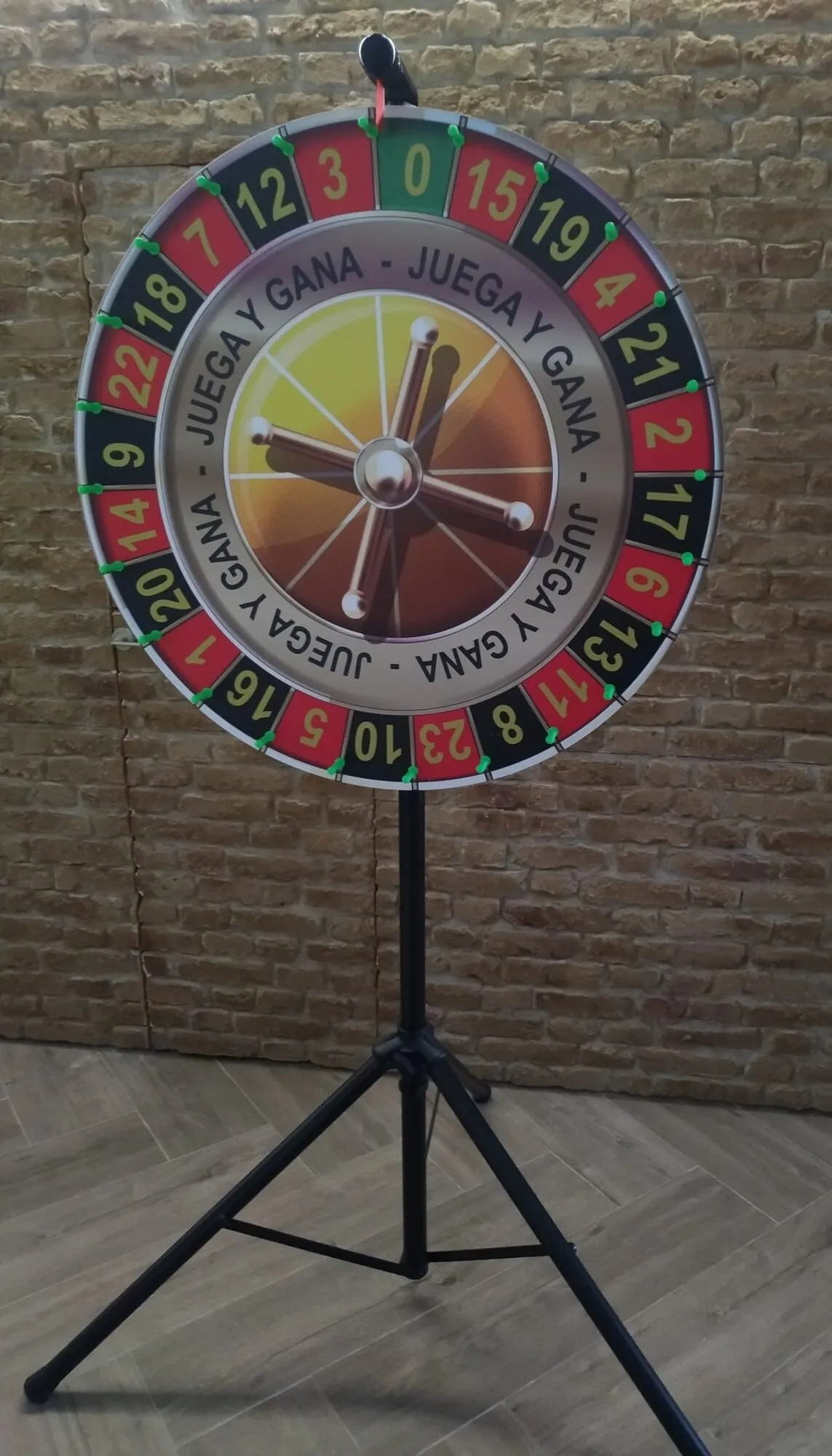 Small prize wheel on a tripod against a brick wall